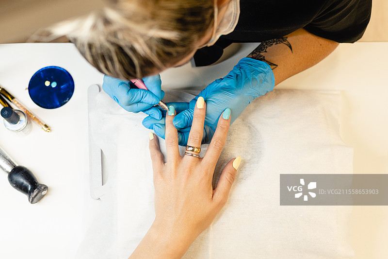 美容师在美容中心为客户涂抹蓝色和黄色指甲油的特写镜头。图片素材