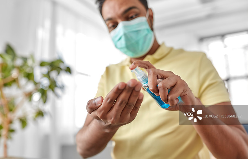 卫生、医疗保健和安全概念 - 印度男子佩戴防护口罩，近距离使用抗菌洗手液。佩戴口罩的男子近距离使用洗手液。图片素材