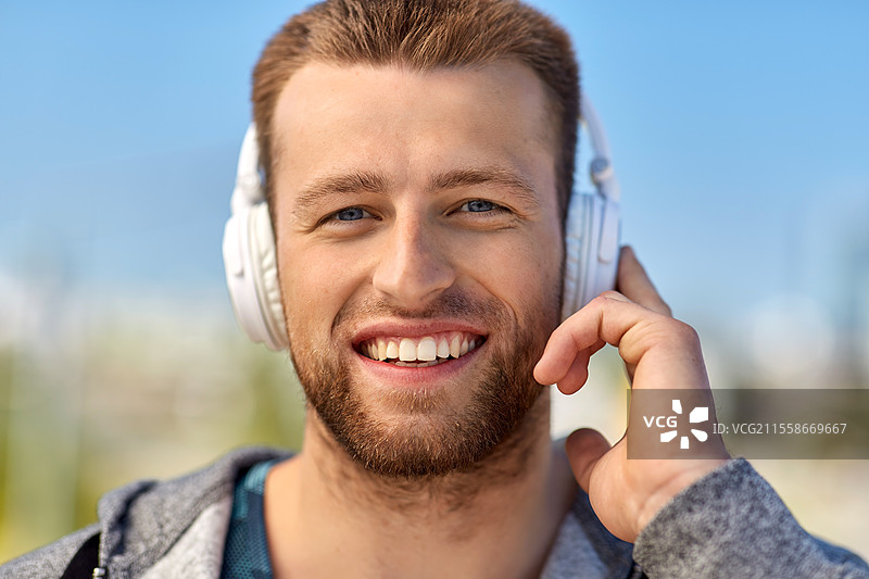 健身、运动和生活方式概念 - 年轻男子在户外戴着耳机听音乐。图片素材