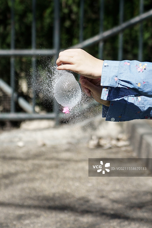 女孩的手在户外用针吹气水球。图片素材