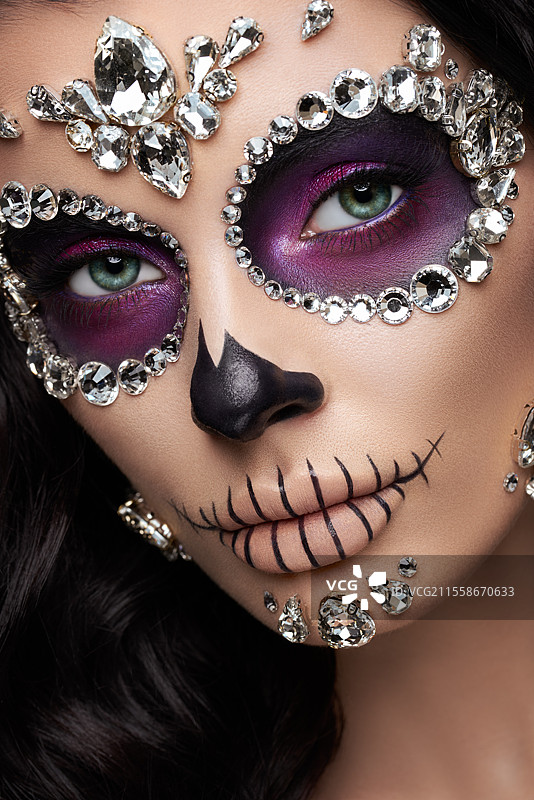 红色背景下的女性肖像，脸上画着糖骷髅妆。万圣节服装和化妆。卡拉维拉·卡特里娜的肖像。图片素材