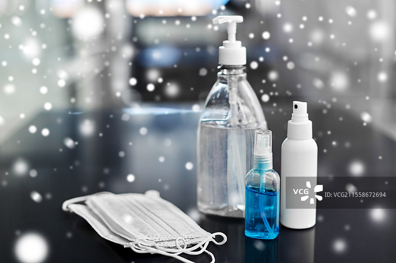 卫生和消毒概念 - 冬季雪地上桌子上不同的洗手液、液体肥皂和面部防护医用口罩的特写。洗手液、医用口罩和液体肥皂。图片素材