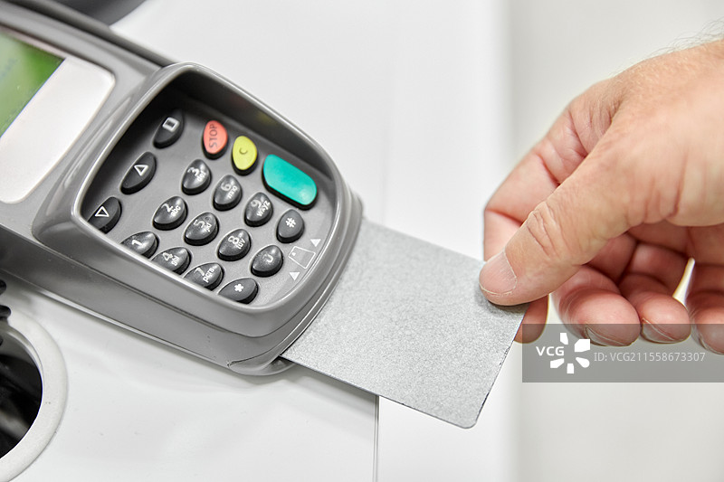 购物、支付和金融概念 - 手握信用卡靠近读卡器的特写。图片素材