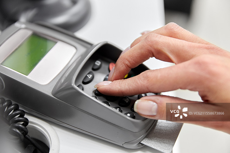 购物、支付和金融概念 - 手部特写，信用卡在读卡器中输入密码。手部特写，信用卡在读卡器中。图片素材