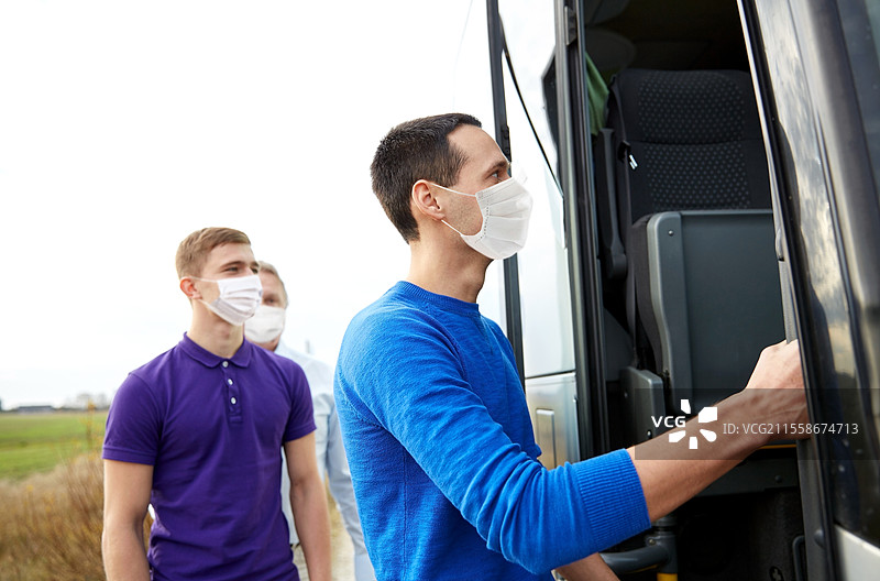 旅游与健康概念 - 一群男性乘客佩戴口罩登上旅游巴士，以防病毒疾病。戴着口罩的乘客们正在登上旅游巴士。图片素材