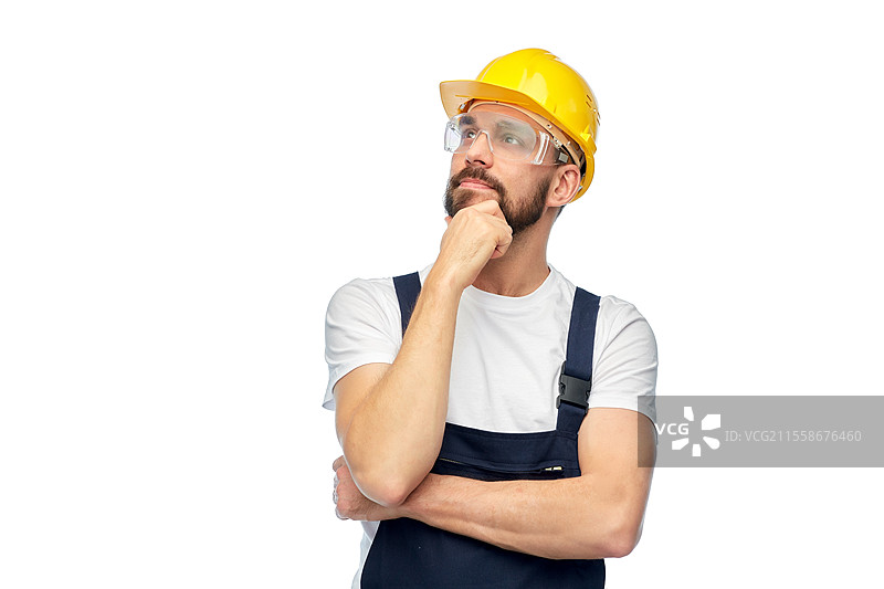职业，建筑和施工 - 思考中的男性工人或建筑工人，戴着黄色安全帽和护目镜，背景为白色。思考中的男性工人或建筑工人双臂交叉。图片素材