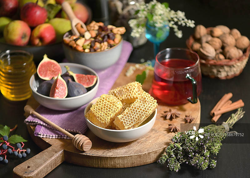 秋季餐桌上的蜂蜜、蜂巢、茶、干果和无花果图片素材