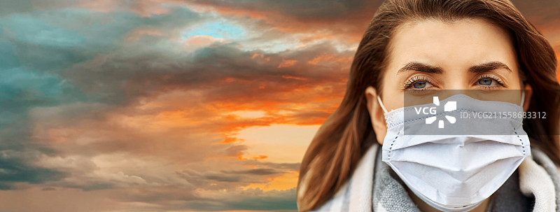 健康、安全和疫情概念 - 年轻女性在日落天空背景下佩戴防护口罩的特写。年轻女性佩戴防护口罩。图片素材