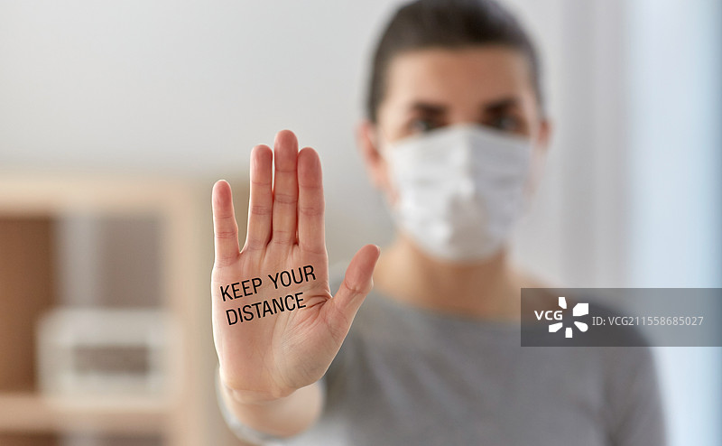 健康、安全和疫情概念 - 年轻女性佩戴防护口罩，做出停止手势并呼吁保持距离。戴口罩的女性呼吁保持距离。图片素材