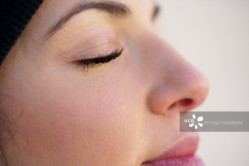 年轻女性靠在墙上，闭着眼睛的特写肖像。生活方式概念。图片素材