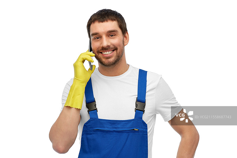 职业、清洁服务和人们的概念 - 穿着工作服和手套的快乐微笑男性工人或清洁工在白色背景上用智能手机打电话。快乐的男性工人或清洁工正在用智能手机打电话。图片素材