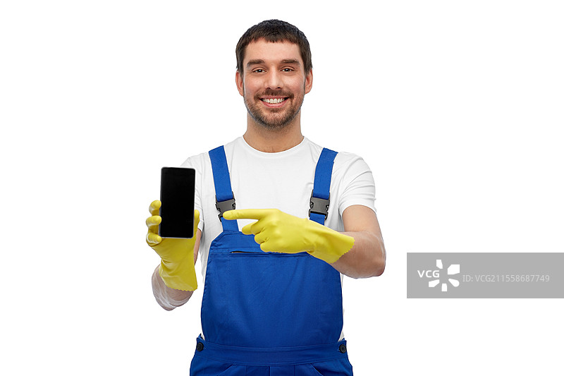 职业、清洁服务和人们的概念 - 开心微笑的男性工人或清洁工穿着工作服和手套，在白色背景下展示智能手机。开心的男性工人或清洁工展示智能手机。图片素材