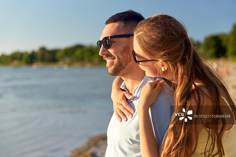 休闲、关系和人际概念 - 戴着太阳镜的快乐情侣在夏季海滩拥抱。快乐情侣在夏季海滩拥抱。图片素材