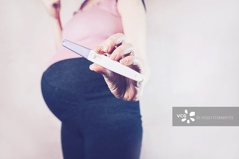 女性手持阳性怀孕测试棒图片素材