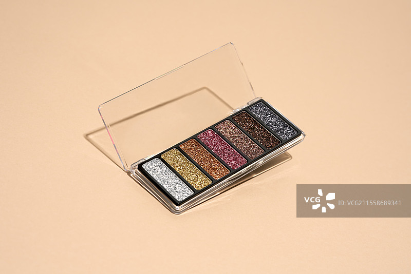 化妆盘漂浮在米色背景上。专业的多色眼影化妆盘。化妆品。图片素材