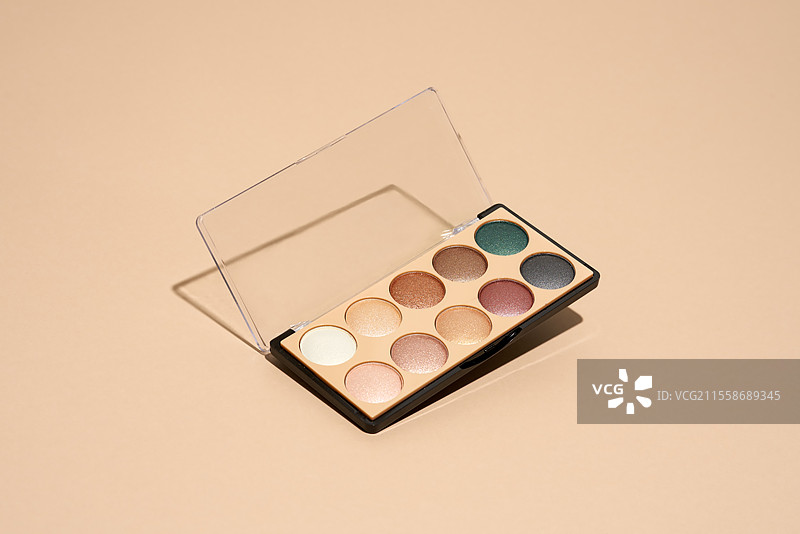 化妆盘漂浮在米色背景上。专业的多色眼影化妆盘。化妆品。图片素材