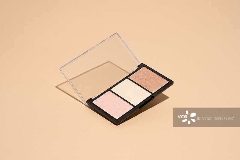 化妆盘漂浮在米色背景上。专业的多色眼影化妆盘。化妆品。图片素材