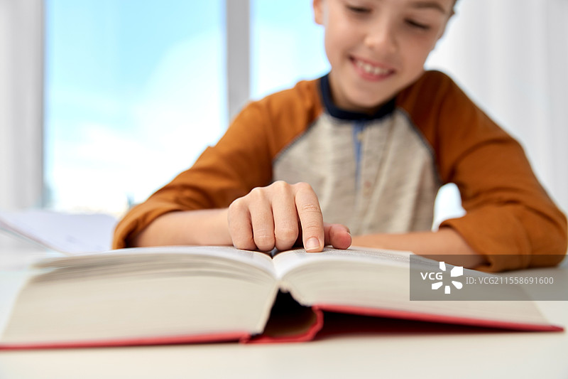 教育、童年、人们、家庭作业和学校概念 - 微笑的男学生在家里用书写笔记本。微笑的男学生在家里写笔记本。图片素材