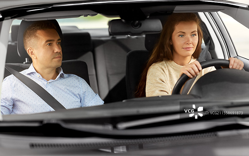 驾驶课程与人们的概念 - 汽车驾驶学校的教练正在教年轻女性驾驶。汽车驾驶学校的教练正在教女性。图片素材