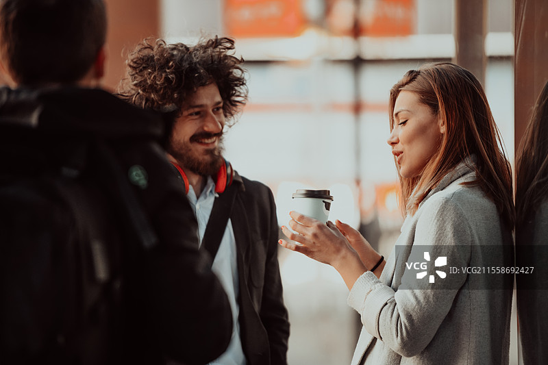 两位年轻人在公司前喝咖啡，休息一下。图片素材