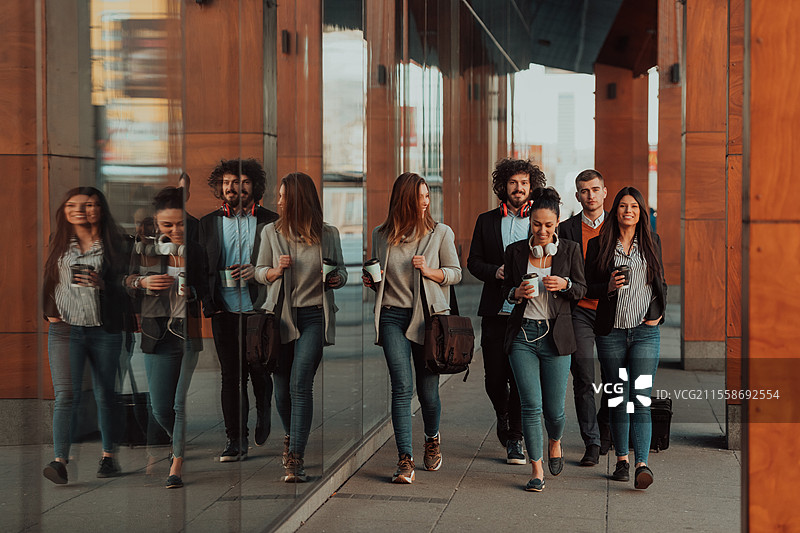 快乐的商务人士在街上走着，讨论成功的交易，结束了一天的工作。高质量照片。优雅的商务人士在现代城市中行走。图片素材