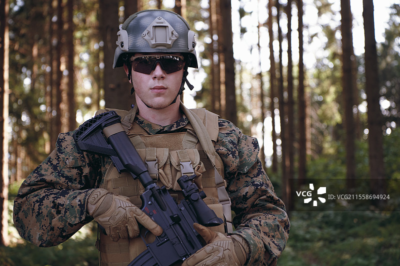 穿着防护军用战术装备和武器的士兵肖像，背景为森林。图片素材