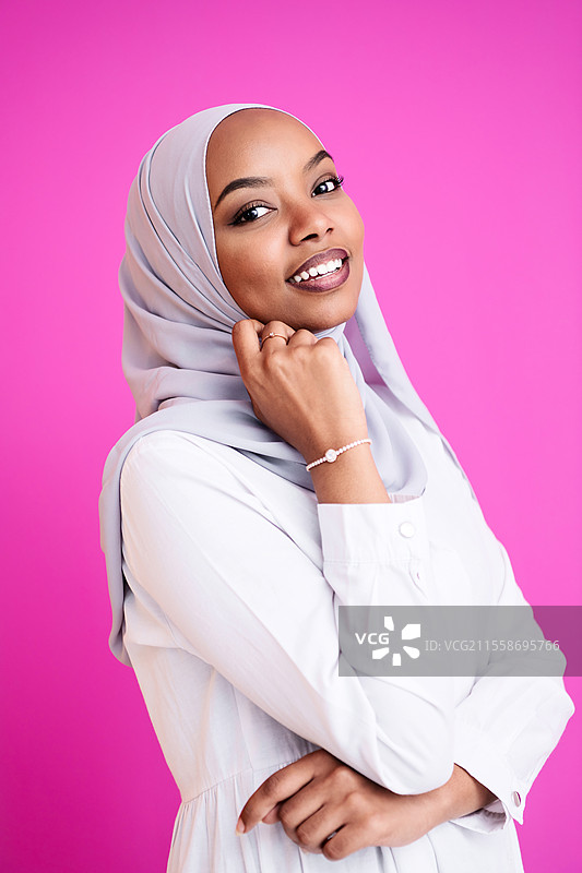 年轻现代穆斯林非洲美女穿着传统伊斯兰服装，背景为粉色塑料。图片素材