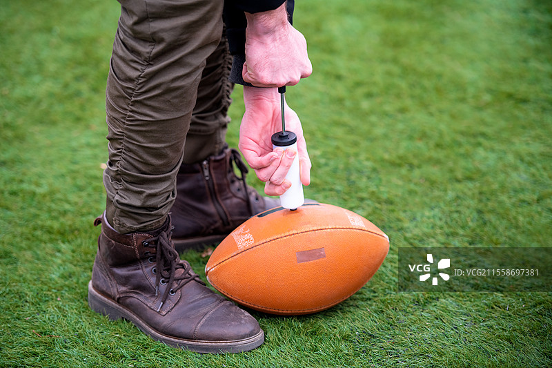 特写镜头：一名男子在球场上为美式足球充气图片素材