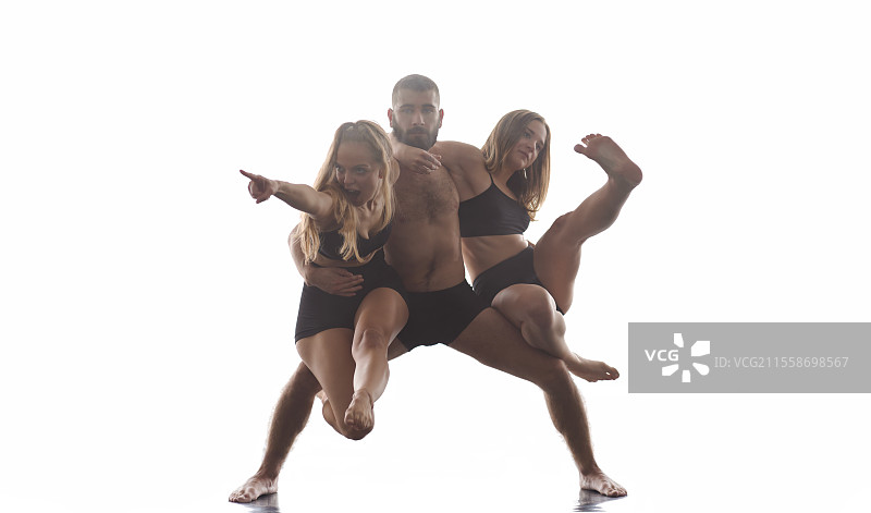 一群年轻的运动舞蹈搭档穿着黑色紧身裤，表演现代风格的芭蕾舞，融入了杂技元素。在白色背景前进行艺术表演的运动芭蕾舞者们。图片素材