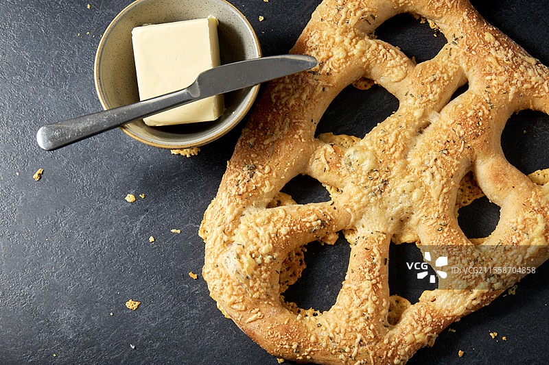 食品、烘焙和烹饪概念 - 厨房桌上的奶酪面包、碗中的黄油和刀具特写。图片素材