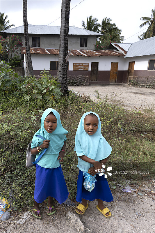 穿着深蓝色长袍和面纱、浅蓝色头巾的小女孩们，正前往坦桑尼亚桑给巴尔的古兰经学校。图片素材