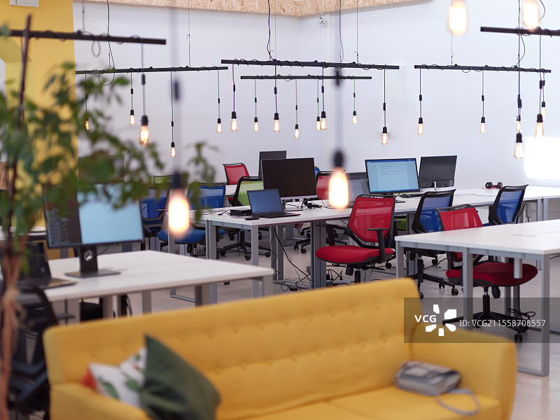 现代空旷的初创公司开放式办公室内部，配有电脑屏幕和时尚的设计家具图片素材