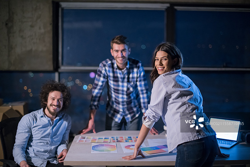 年轻的商业团队在建筑工地上，建筑师和工程师正在检查文件和业务流程，使用笔记本电脑在新创办的办公室里工作，夜间进行。图片素材