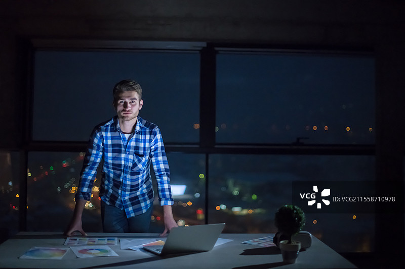 年轻男性工程师在建筑工地上检查文件和商业流程，夜间在新创办公室使用笔记本电脑的肖像图片素材