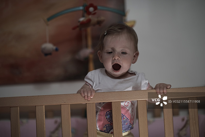 可爱的一岁小宝宝在床上玩玩具，迈出第一步，学习走路。图片素材