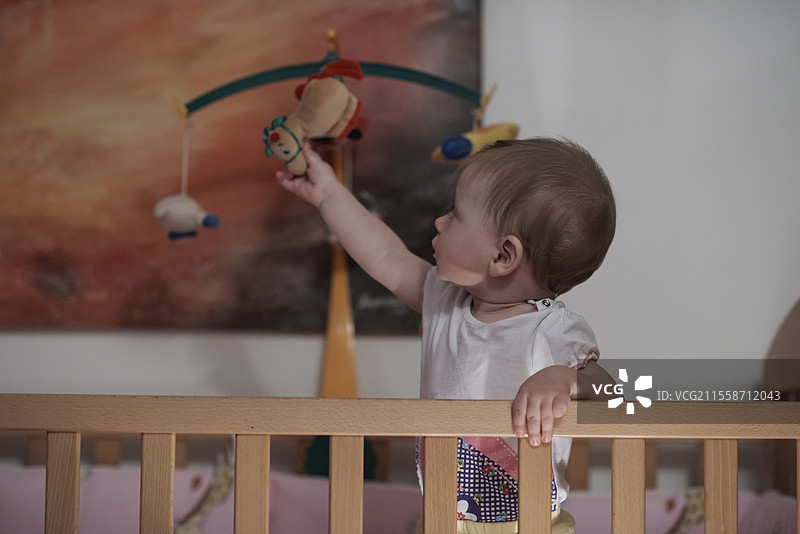 可爱的一岁小宝宝在床上玩玩具，迈出第一步，学习走路。图片素材