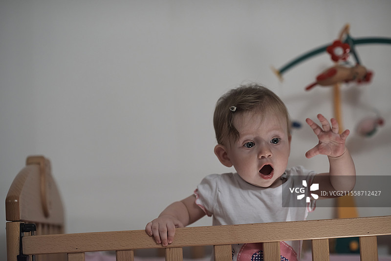 可爱的一岁小宝宝在床上玩玩具，迈出第一步，学习走路。图片素材