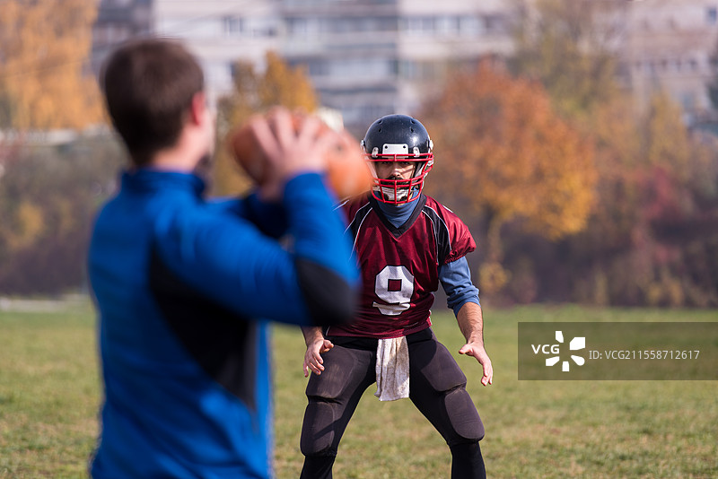 教练在训练场上将球扔向一群年轻的美式足球运动员，场面十分激烈。图片素材
