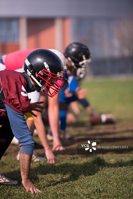 一群年轻的美式足球运动员在场地上训练时的动态场景图片素材