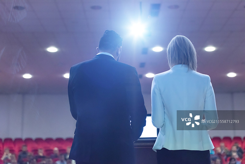 两位年轻的商务人士在会议室向坐在椅子上的同事们进行演讲图片素材