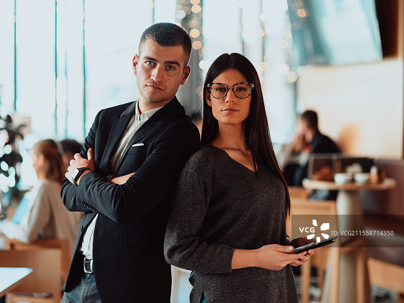 一幅年轻人站在办公室使用平板电脑的肖像。前景是一组以女性领导为主的商务人士。图片素材