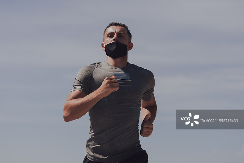 年轻男女在早晨户外佩戴防护口罩跑步和锻炼。运动，积极生活，疫情期间的慢跑。新冠疫情后的新常态。高质量照片。选择性聚焦。图片素材