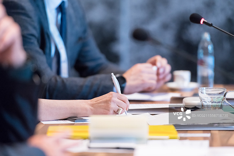 商务人士的手在现代会议室的商业研讨会上使用钢笔做笔记，特写镜头。图片素材