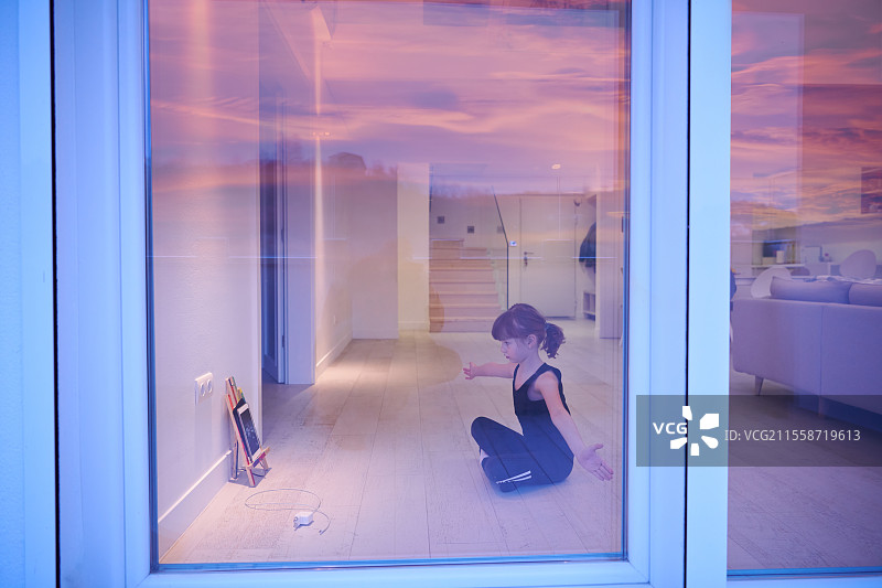 小女孩在家中观看平板电脑进行在线培训，同时进行健身和现代芭蕾舞练习。现代芭蕾舞学校的在线教育概念课程。在疫情隔离期间保持社交距离，自我隔离的居家时光。图片素材