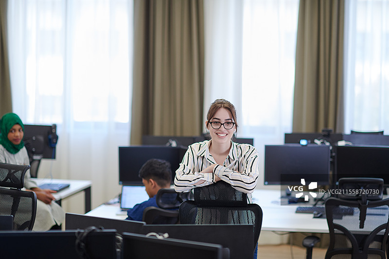 现代初创公司开放式办公室内，穿着休闲服装、戴着眼镜的女商人肖像图片素材