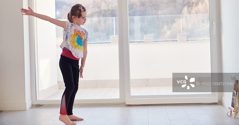 小女孩在家通过平板电脑进行在线培训，正在做现代芭蕾舞练习。现代芭蕾舞学校的在线教育课程。在疫情隔离期间保持社交距离，自我隔离。图片素材