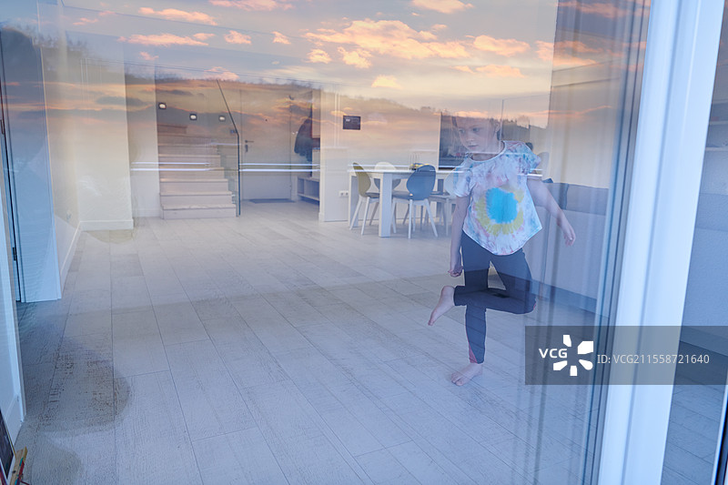 小女孩在家通过平板电脑进行在线培训，正在做现代芭蕾舞练习。现代芭蕾舞学校的在线教育课程。在疫情隔离期间保持社交距离，自我隔离。图片素材