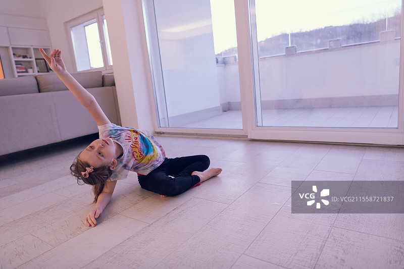 小女孩在家通过平板电脑进行在线培训，正在做现代芭蕾舞练习。现代芭蕾舞学校的在线教育课程。在疫情期间保持社交距离，自我隔离。图片素材