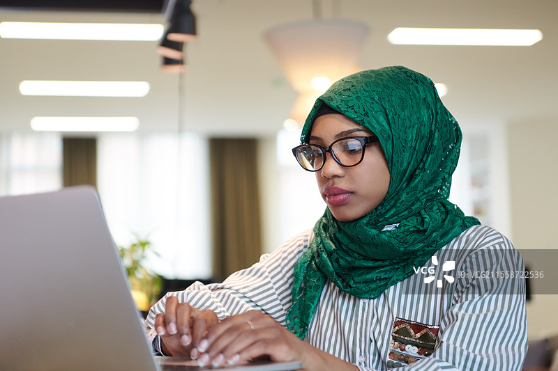 年轻的现代穆斯林阿拉伯商人穿着传统服装，在家中使用智能手机图片素材