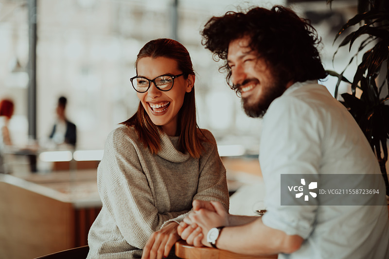 一位戴眼镜的女性和几位有非洲卷发的男性坐在咖啡馆里讨论商业项目。商业情侣在工作日后坐在咖啡馆里。图片素材